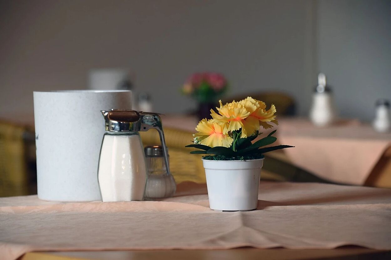 A table with a pitcher, salt and pepper shakers, and a small potted plant with yellow flowers.