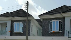 A two-story residential building with a modern design, featuring a balcony on the upper floor and a lattice fence in front. - Mac View Hotels (Owerri)