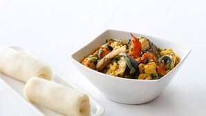 A white bowl of seafood stew with a white plate beside it. - Mac View Hotels (Owerri)