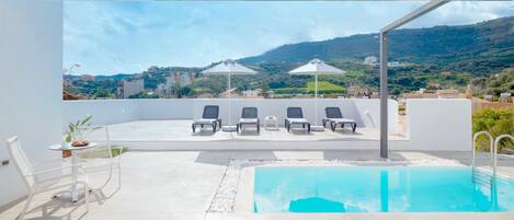 Alberca al aire libre, sombrillas en la alberca y camastros