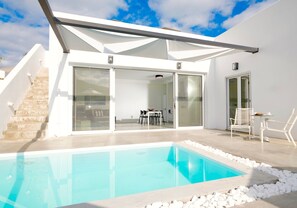 A modern house with a swimming pool, a covered patio, and a staircase leading to an upper level.