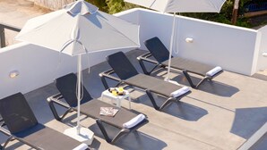 A rooftop lounge area with sun loungers, umbrellas, and a small table with a magazine and a drink. - Paradiso II (Malevizi)