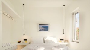 Ein modernes Schlafzimmer mit einem großen Bett, zwei Nachttischen, einem Schminktisch und einem gerahmten Bild an der Wand, sowie einem Fenster mit Blick.