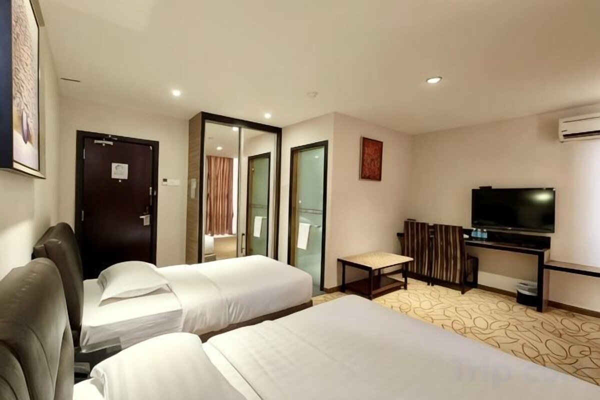 Una habitación de hotel con dos camas, televisión, escritorio y espejo.