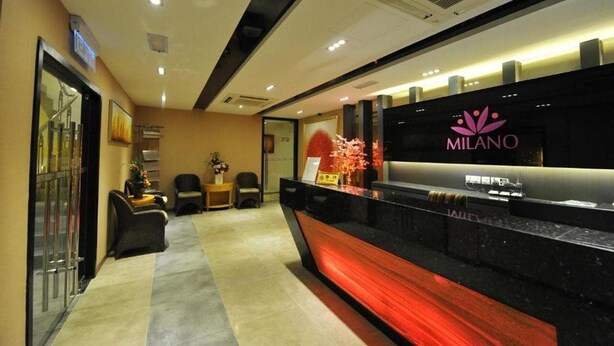 A reception area with a black counter, a sign reading "MILANO," and a reception desk. - Milano Hotel (Kluang)