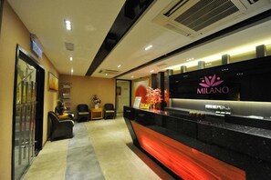 A reception area with a black counter, a sign reading "MILANO," and a reception desk. - Milano Hotel (Kluang)