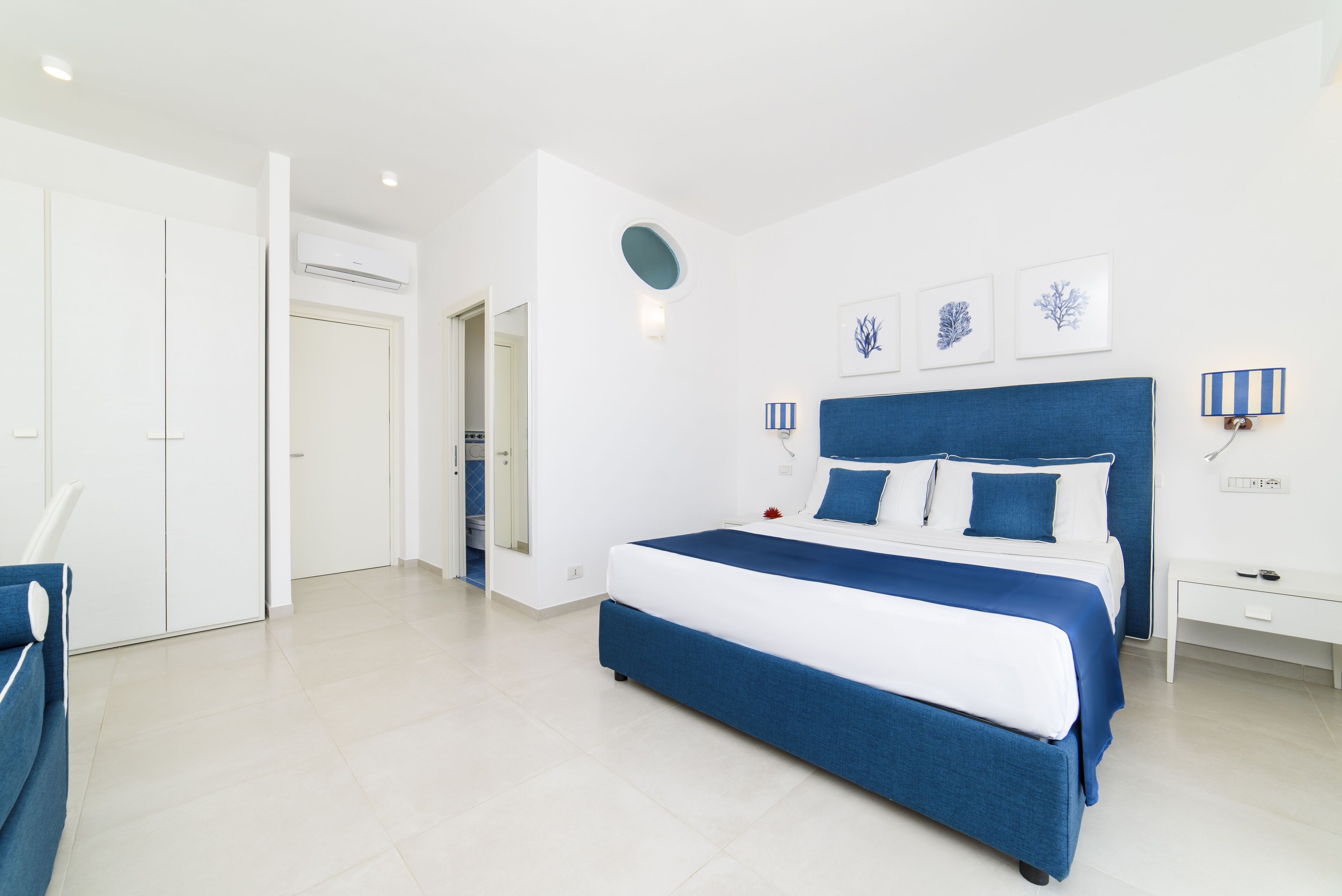 Une chambre moderne avec un grand lit, des murs blancs et un mur d’accent bleu.