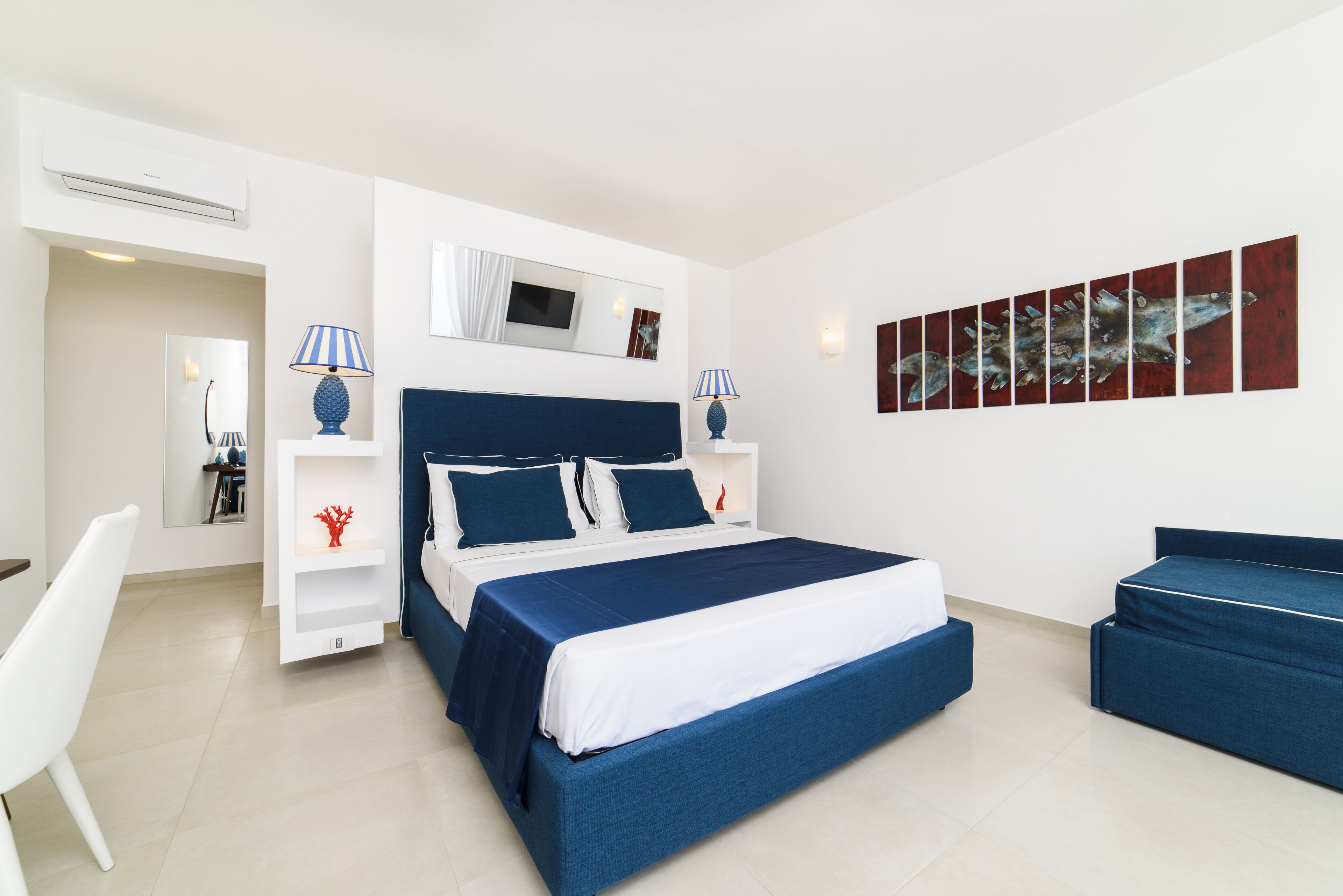 A modern bedroom with a large bed, bedside tables, a desk, and a chair.