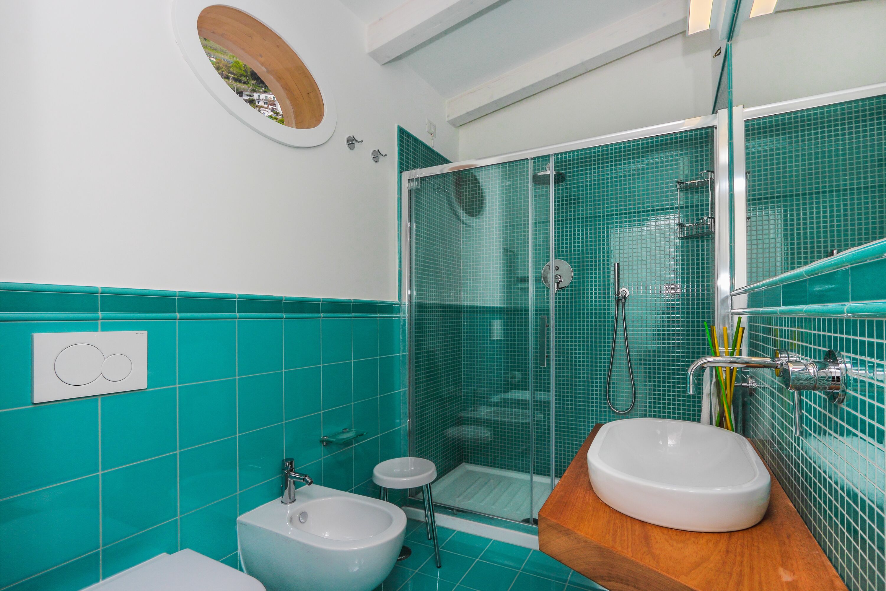A bathroom with a glass shower enclosure, a white sink, and a bidet.