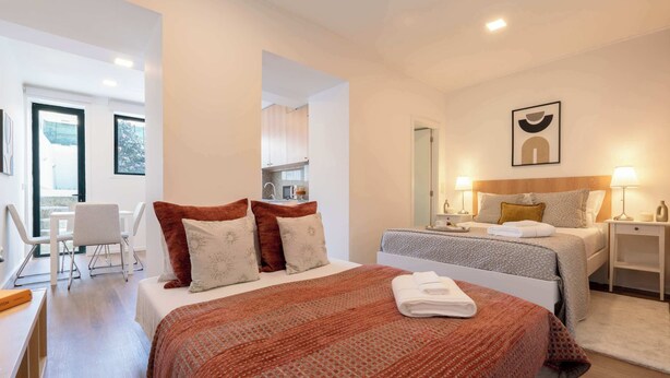 A modern hotel room with a large bed, a desk, a chair, and a view of the outside.