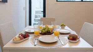 A breakfast table set with plates, glasses, and a bowl of fruit.