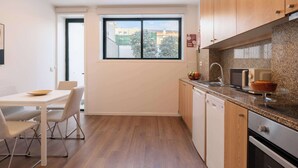 A modern kitchen with wooden cabinets, a built-in oven, a microwave, and a window with a view of buildings and trees.