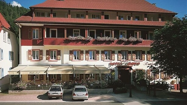 A two-story building with a red roof and multiple windows. There is a sign that reads "Hotel Queen." - Hostel zum Löwen (Todtmoos)