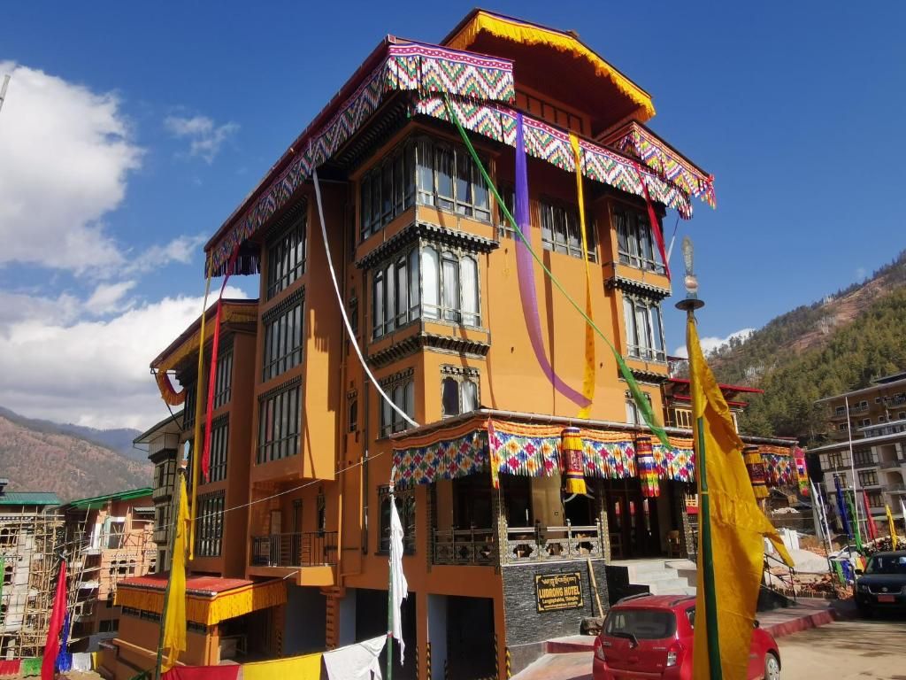 Een meerlaags gebouw in traditionele stijl, met balkons en een bord waarop staat dat het een hotel is.