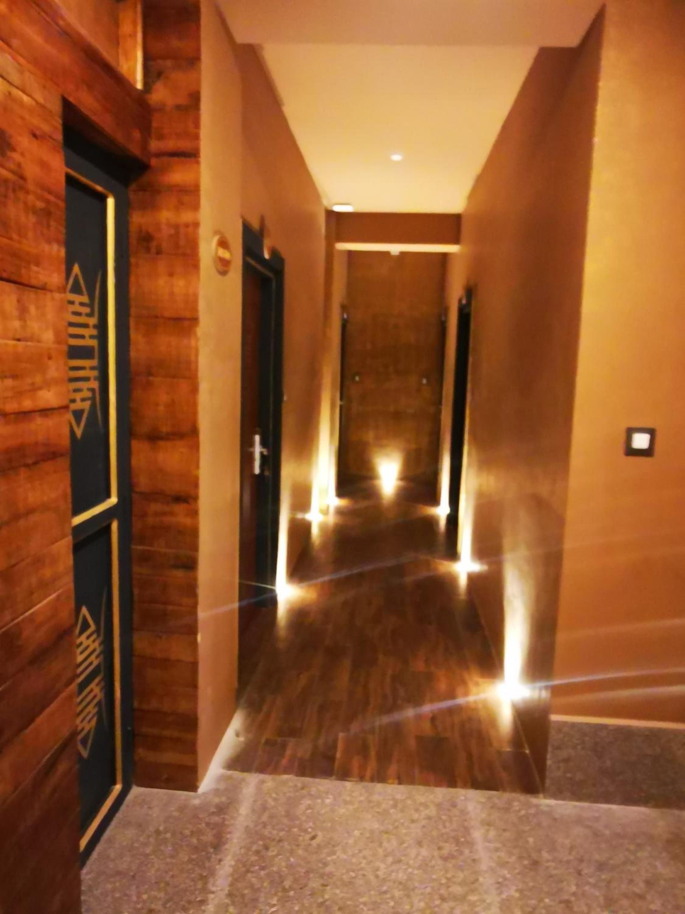 A hotel hallway with wooden walls, a carpeted floor, and a door with a logo.