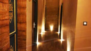 A hotel hallway with wooden walls, a carpeted floor, and a door with a logo.