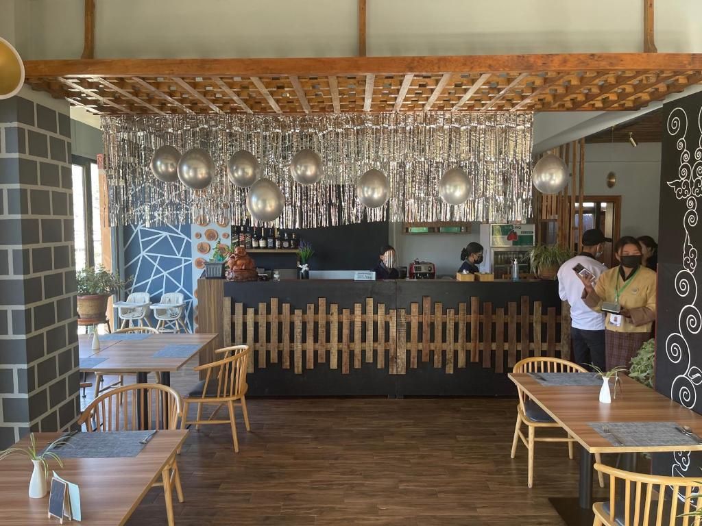 Interior de restaurante con mesas de madera, una barra y adornos metálicos colgantes.
