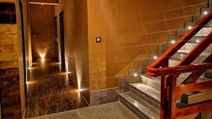 Pasillo de hotel con suelo de madera y una escalinata de mármol con barandillas de madera.