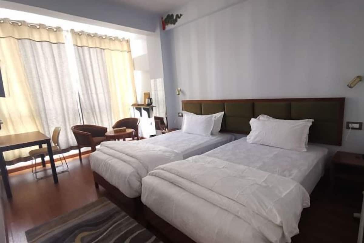 A hotel room with two beds, a desk, and a chair.