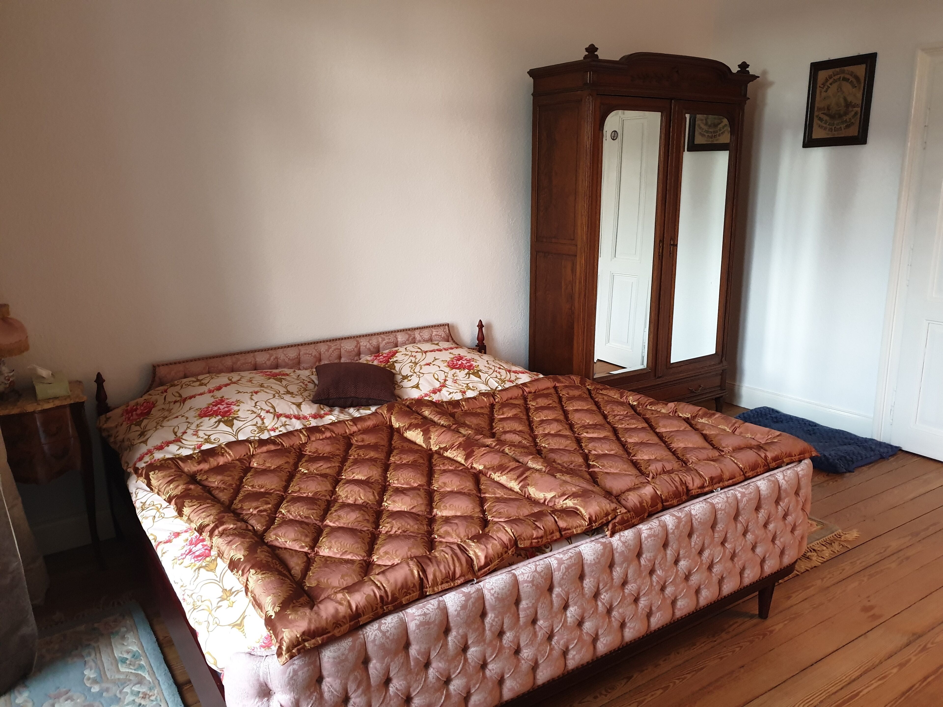 Un dormitorio con una cama grande, un armario de madera y un espejo.