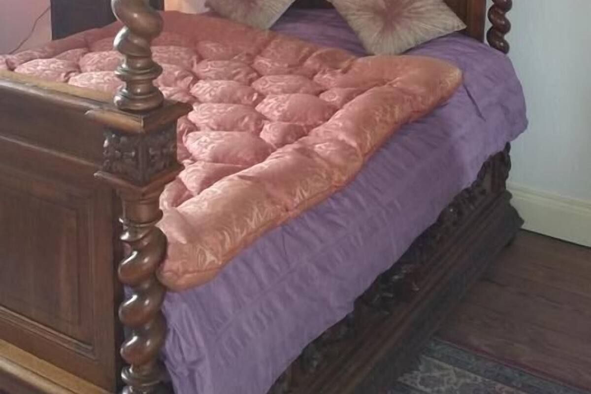 A four-poster bed with a wooden frame and a purple bedspread.
