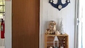 A room with a wooden door, a wall-mounted anchor decoration, and a small wooden shelf with various items. - Little Blue Shack
Check-in 9:00 am
Check-out 4:00 pm (Culebra)