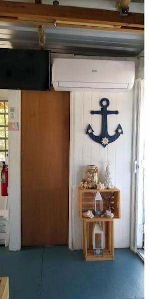 Une pièce avec une porte en bois, un décor mural représentant une ancre et une petite étagère en bois sur laquelle sont disposés divers objets.