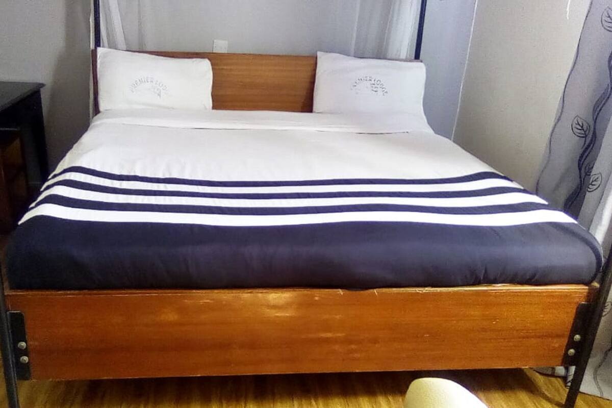 A bed with a wooden frame, white and navy blue striped bedding, and two white pillows.