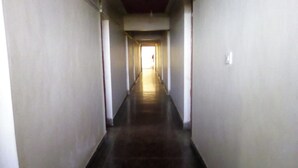 A long, narrow hallway with white walls and a dark floor, leading to a bright exit at the end. - Scarlet Holiday Inn (Nakuru)
