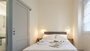 A neatly made bed with white linens, a bedside table with a book and a bottle, and two wall-mounted lights. - Central Station Apartment by Mmega (Florence)