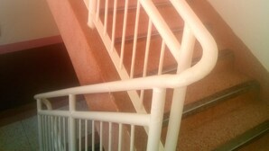 Una escalera con barandas blancas y piso cubierto de moqueta marrón.