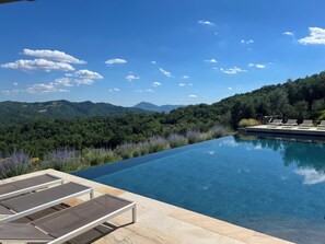 An infinity pool with lounge chairs, surrounded by lush greenery and mountains. - Villa on Umbria Tuscany border, sleeps 12, stunning infinity pool superb views, (Montone PG)