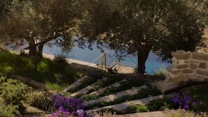 Una scalinata in pietra conduce a una spiaggia, con ringhiera in legno e muretto.