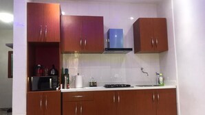A kitchen with wooden cabinets, a microwave, a stove, and a sink. - F2 UDDERS AT MAYAA (Ngor)