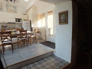 Kitchen area with dining table for four, microwave, refrigerator, and chalkboard.
