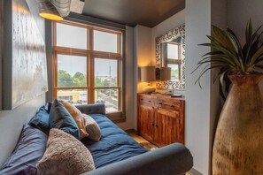 Una sala de estar acogedora con un gran ventanal, un mueble de madera y una planta en maceta.