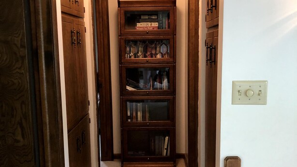 A narrow hallway with wooden cabinets on either side and a bookshelf in the center.