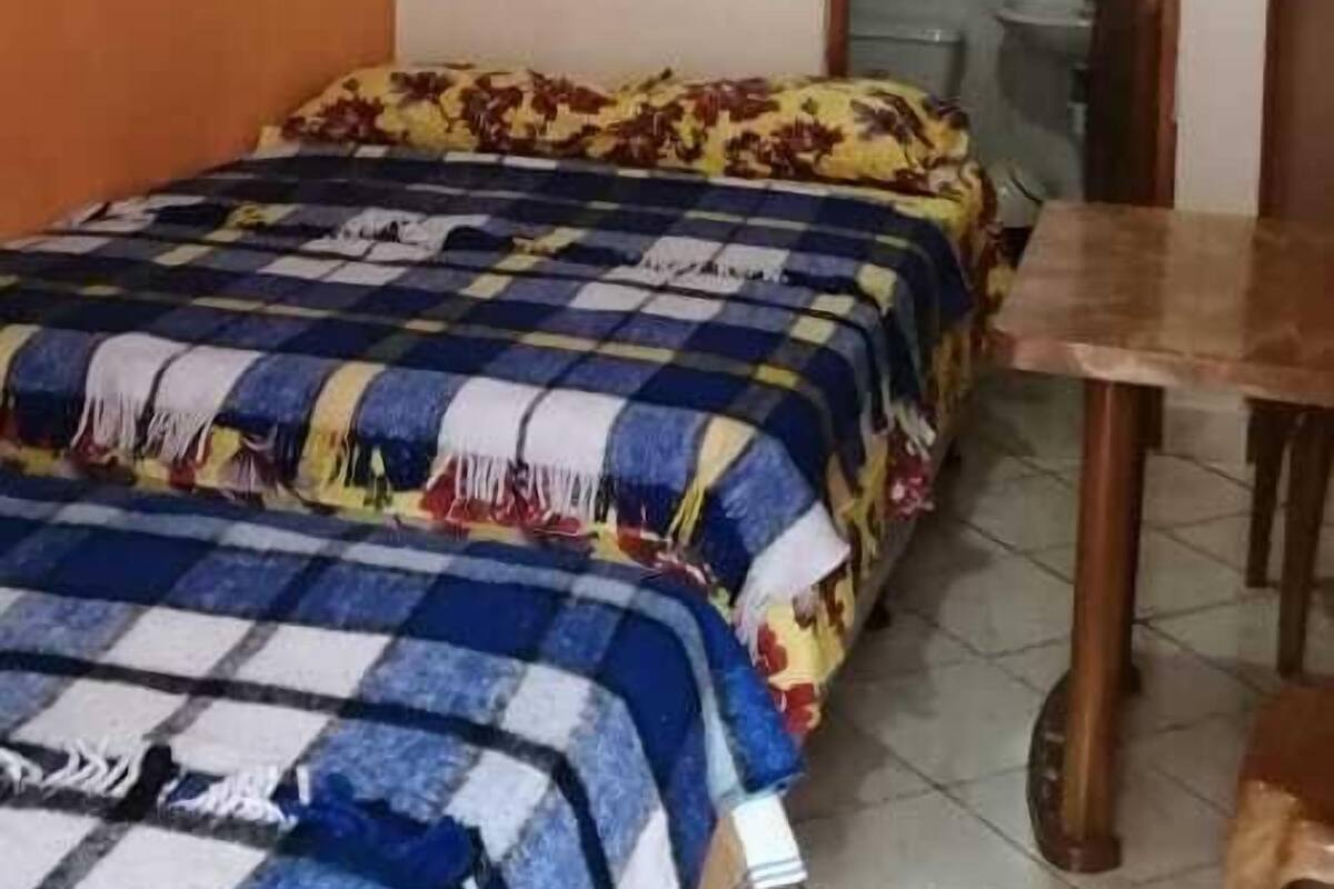 A bedroom with a bed, a wooden table, and a mirror.
