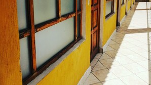 A corridor with yellow walls and wooden doors, leading to multiple rooms. - Posada el mesón xela (Quetzaltenango)