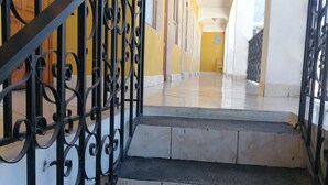 A staircase with ornate black metal railings leading to a hallway with yellow walls and white trim. - Posada el mesón xela (Quetzaltenango)