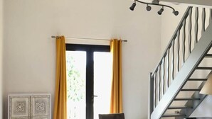 A dining area with a long table, chairs, a cabinet, and a staircase. - Gîte Villa Sous Les Pins (LA LONDE LES MAURES)