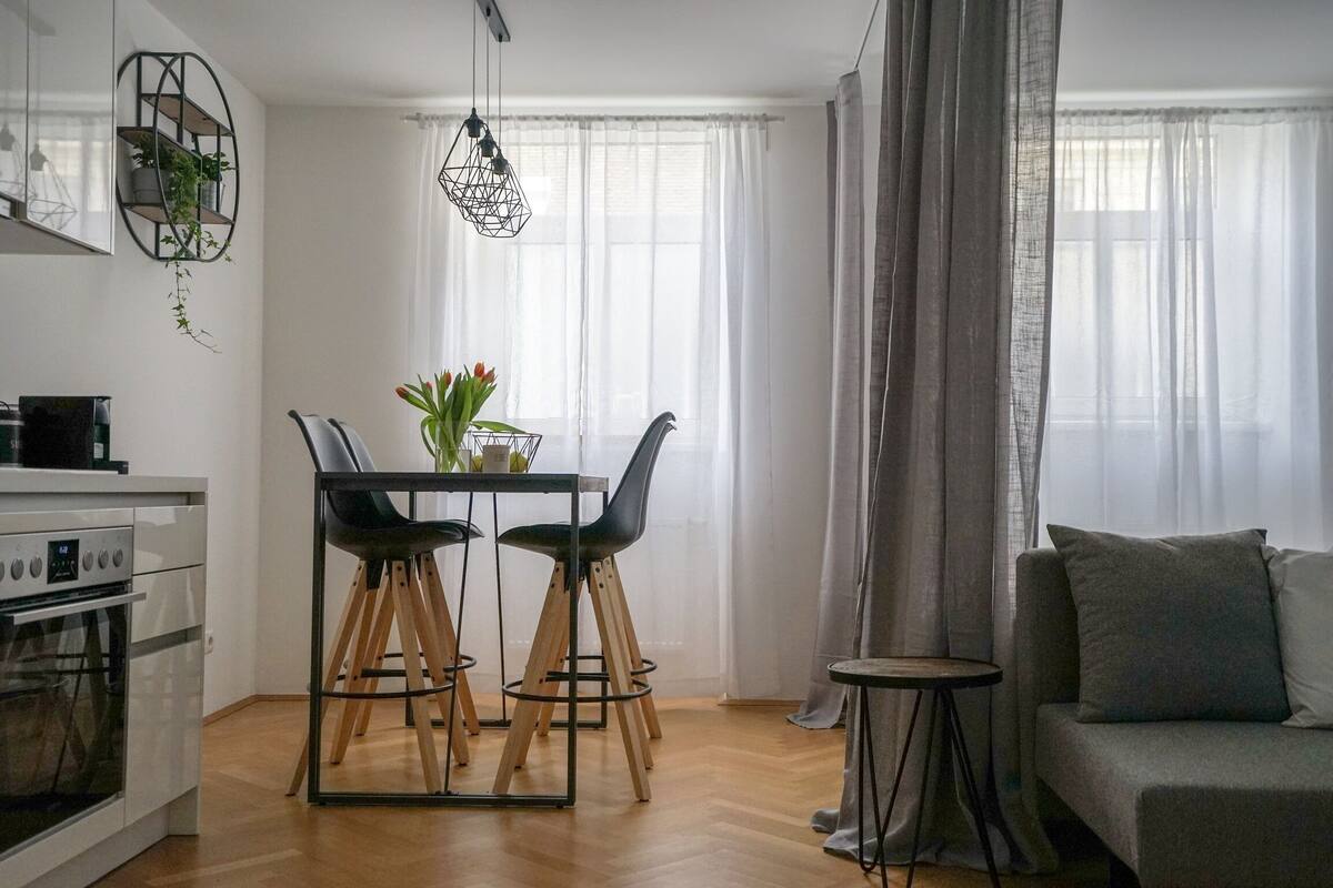 A modern kitchen with a dining area, a sofa, and a small side table.