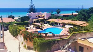 A resort with a swimming pool, beach view, and Mediterranean-style architecture.