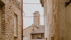 A narrow cobblestone alleyway between buildings with exposed brick walls and a small, tiled-roofed structure in the background. - La casa nel vicolo a Borgo Loretello (Loretello)