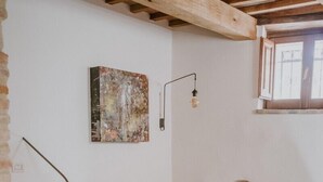 Ein gemütliches Wohnzimmer mit Kamin aus Stein, einem weißen Sofa, einem roten Sessel und einem Holztisch mit einem Glas.