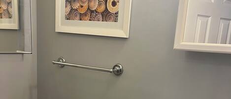 A bathroom with a toilet, sink, and framed artwork on the wall.
