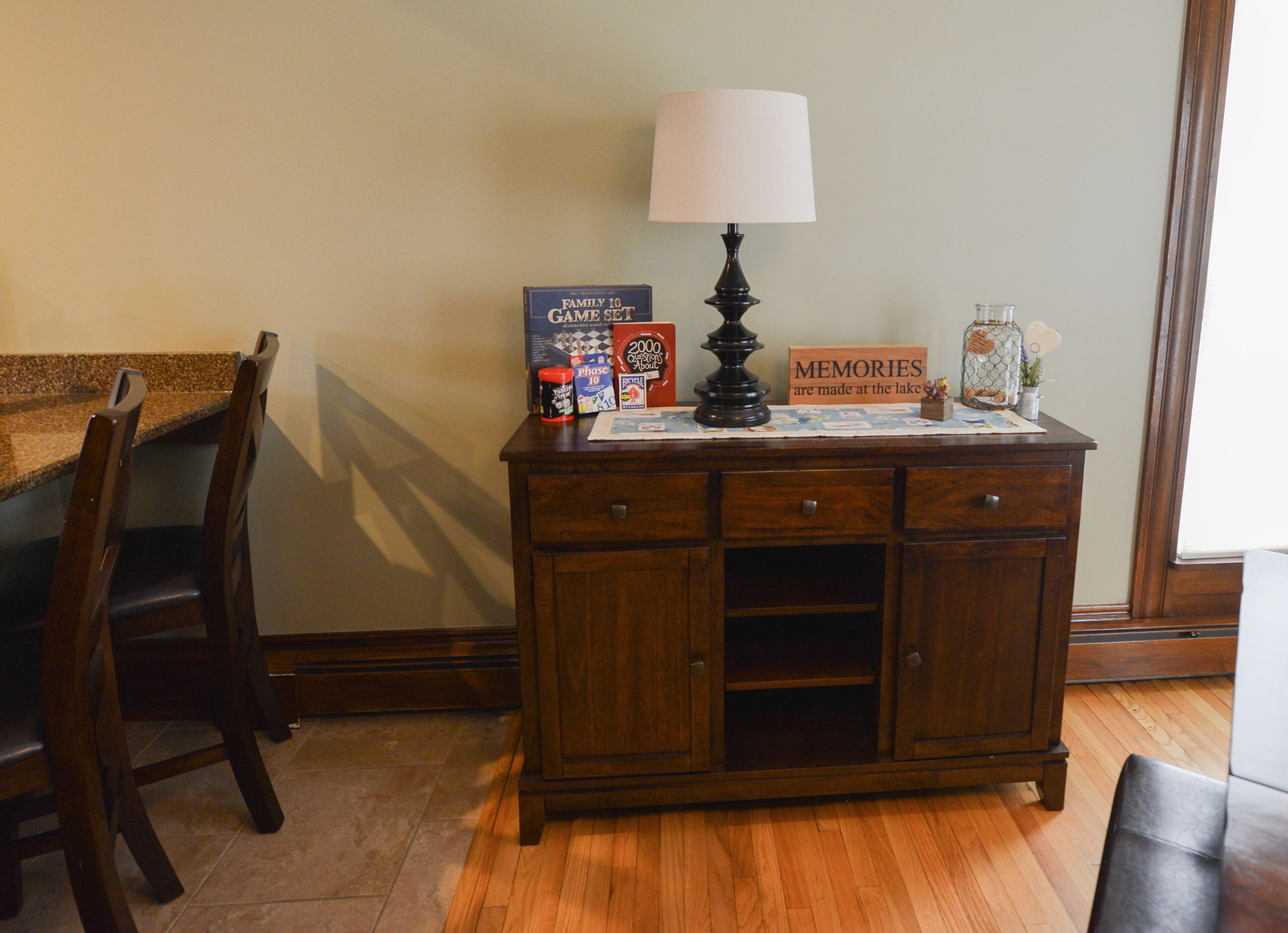 A wooden cabinet with drawers, a lamp, and a game set on top.