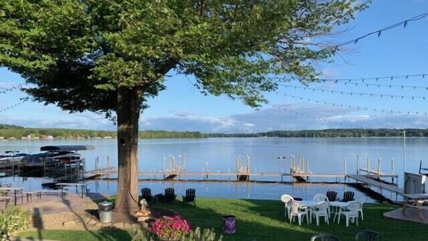 A lakeside patio with outdoor seating, a dock, and boats.