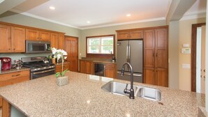 A kitchen with granite countertops, stainless steel appliances, wooden cabinets, and a window with a view.