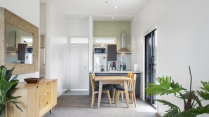 Une cuisine moderne avec une table et des chaises en bois, un four à micro-ondes et un réfrigérateur.